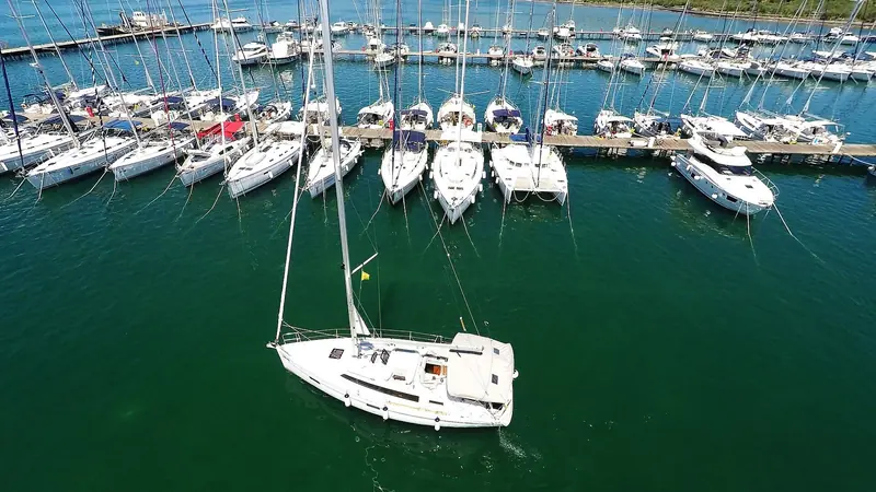 A sailboat leaves Marina Punat, the mouth of Puntarska Draga bay opening onto the wider channel.