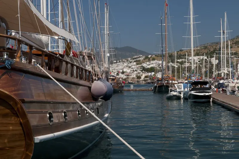 Gulet bows on the marina pontoons. Traditional wooden charter boats and modern yachts share this water and there is no getting away from that.