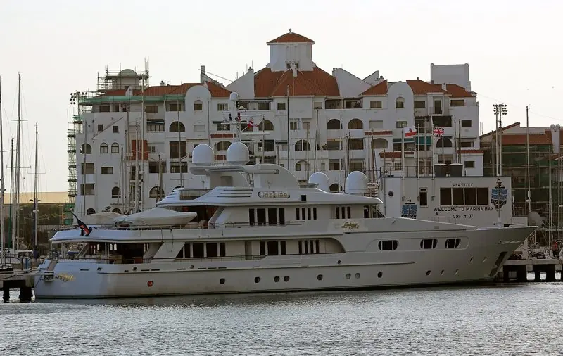 Alongside the Marina Bay pier office sits a white motor yacht of an older generation, the apartment terraces close enough that it is under a minute from passerelle to a restaurant table.
