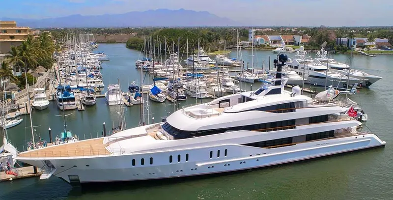 A megayacht on the outer channel with the mountains of the Riviera Nayarit behind, the depth that lets Paradise Village take vessels well past 60 metres