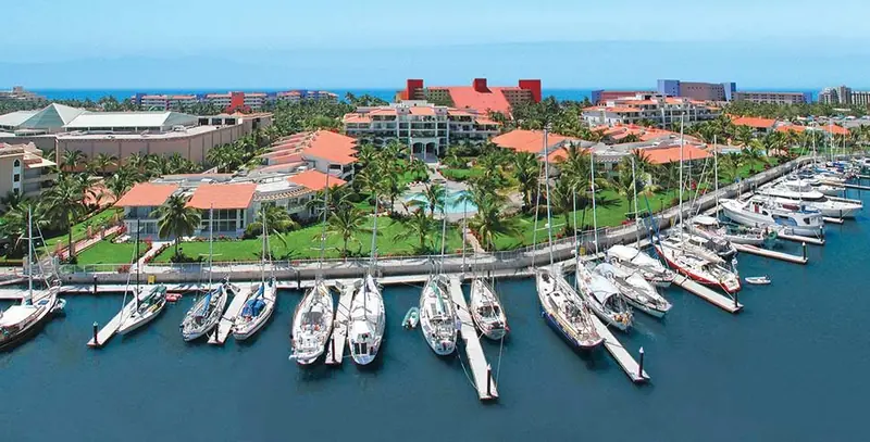 The dockside promenade running the length of the marina, with the resort's red-roofed towers and pool terraces along the water