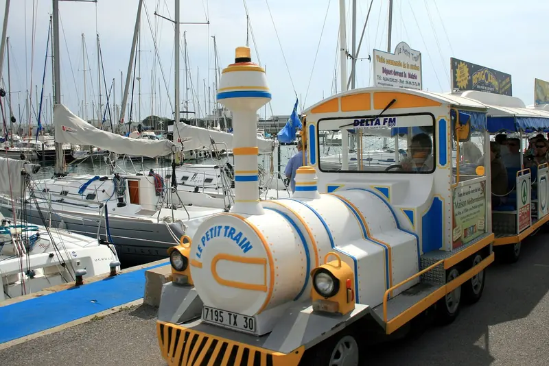 Yacht masts crowd the quay behind Le Petit Train, the tourist tram that runs the length of the marina's canals.
