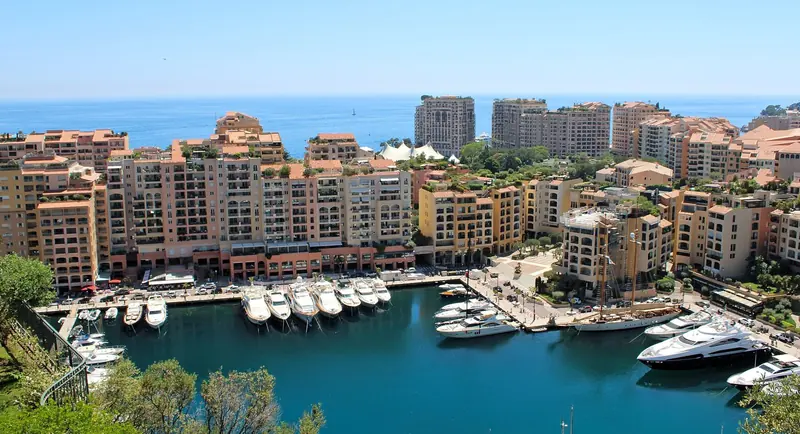 Port de Fontvieille from above. The basin is round rather than a long quay wall, and the 30 metre ceiling is obvious the moment you see what is actually tied up in it.