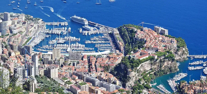 Fontvieille in the foreground from La Turbie, with the Rock and Port Hercule beyond it. The two Monaco harbours read as one bay from up here and function as two different marinas down at water level.