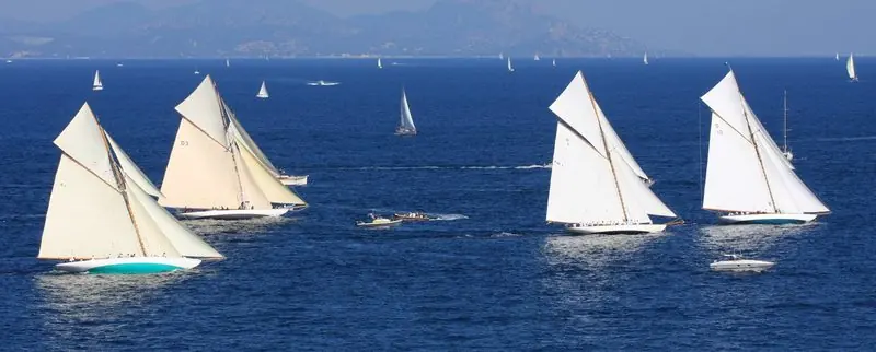 Out in the gulf classic gaff cutters race under full sail in the regatta season, the red rock of the Esterel standing behind them.