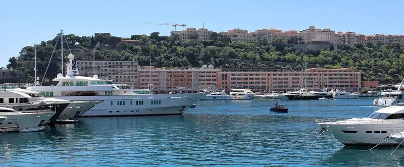 A large motor yacht inside the harbour, with the old town on the Rock behind it.