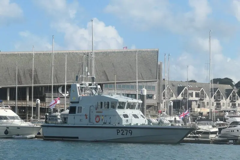 Alongside the quay a small naval patrol boat sits among the yacht berths, with the museum and the harbourside houses behind.