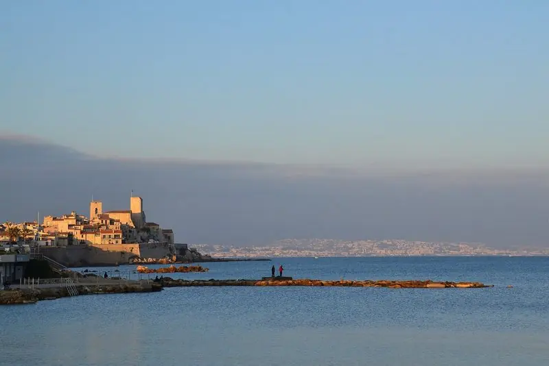 The ramparts of Antibes old town seen from the water, with the Alps behind on a clear day.