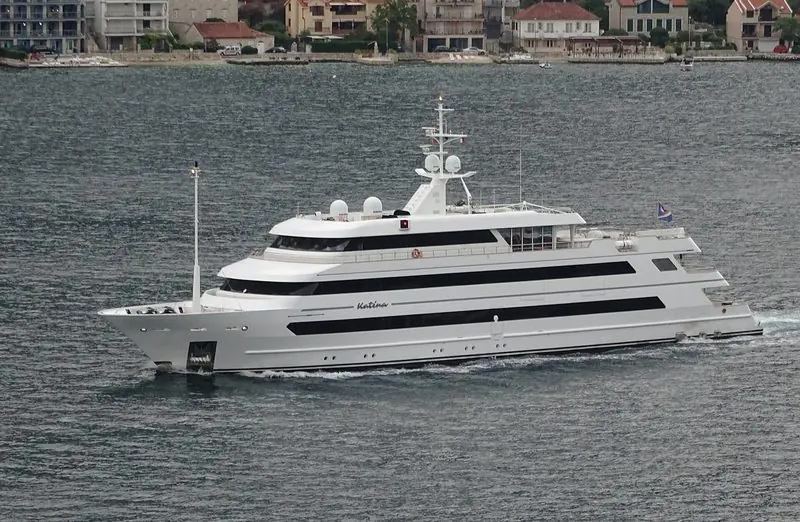 A motor yacht underway in the bay, with the shoreline villages behind.