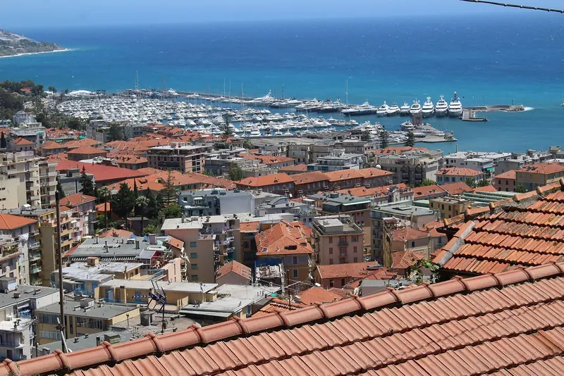 Portosole seen from the old town on the hill above, the marina's basin and breakwater visible beyond the rooftops of the city centre.