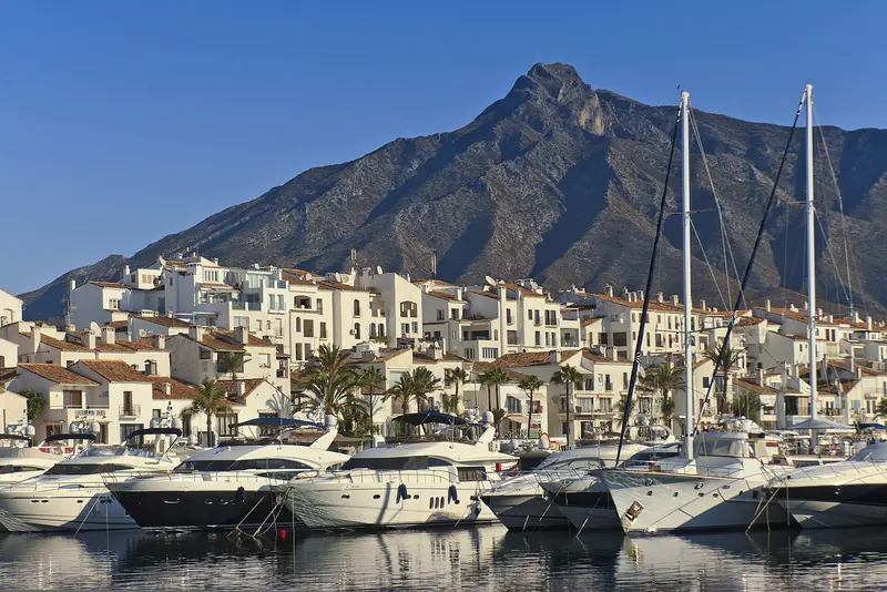 Puerto Banus with La Concha behind it. The whitewashed village around the water is what the address trades on.