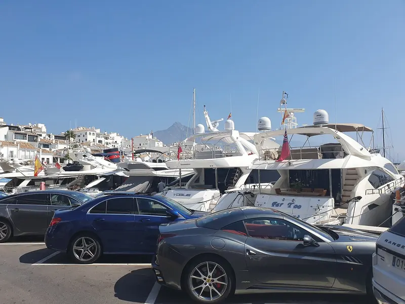 Cars parked on the quay beside the boats. Puerto Banus is as much a promenade as a harbour, and the front row is a stage.