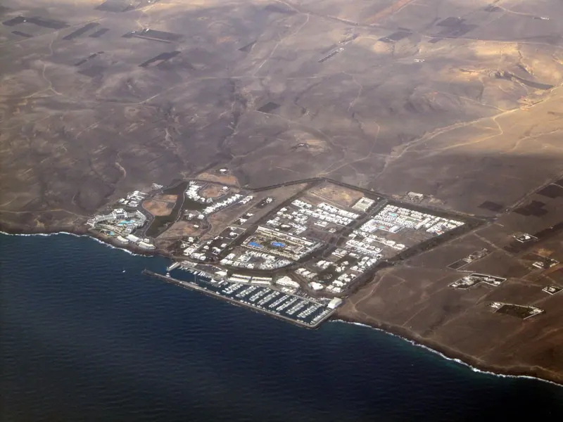 The marina from the air, the breakwater arm and the low white development that is the whole settlement.
