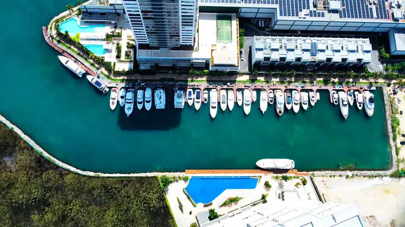 Dock 7 at Puerto Cancun Marina from directly overhead, sport-fishers and flybridge motoryachts packed bow to stern along the canal below the Marina Condos tower.
