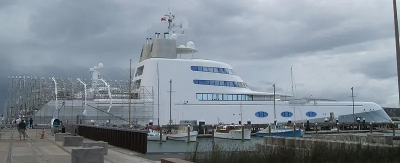 Alongside the wharf sits a very large white motor yacht, dwarfing the classic launches lying on the pontoons in front of her.