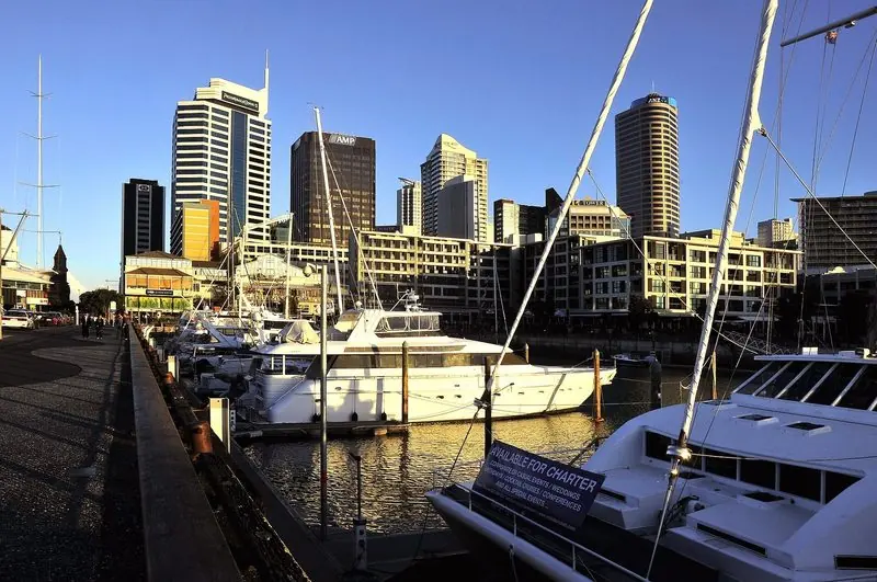 Late sun rakes across the basin and the restaurant terraces on the quay, motor yachts lying only a few metres from the tables.