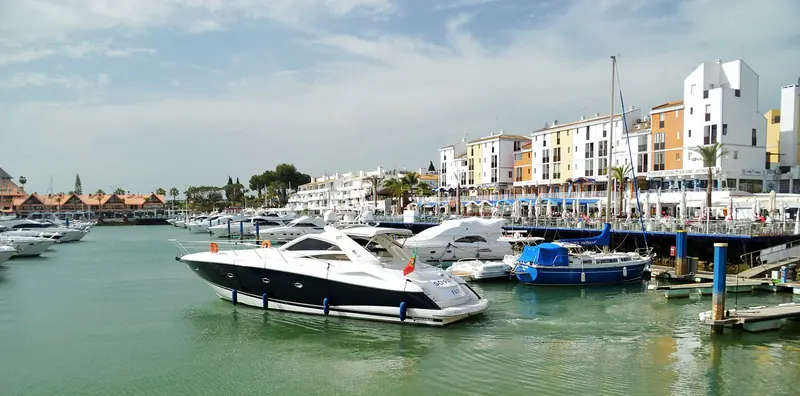 Motor yachts on the pontoons with the apartment blocks that ring the basin behind them.