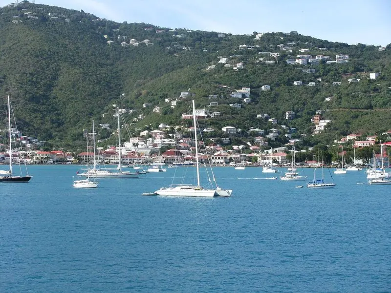 Cruising yachts and a large catamaran ride at anchor off the old town waterfront, shops and restaurants a dinghy ride away across the water.