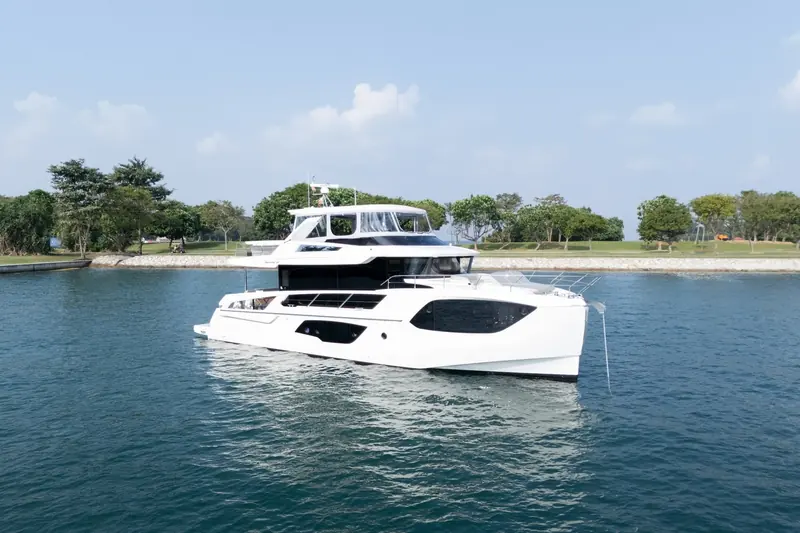 A current-generation Navetta 64 at anchor off a coastal park.