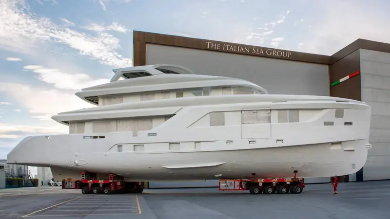 Hull No. 1 of the Admiral A-40 line rolls out of The Italian Sea Group's Marina di Carrara shed on a self-propelled modular transporter, still in bare primer ahead of outfitting.