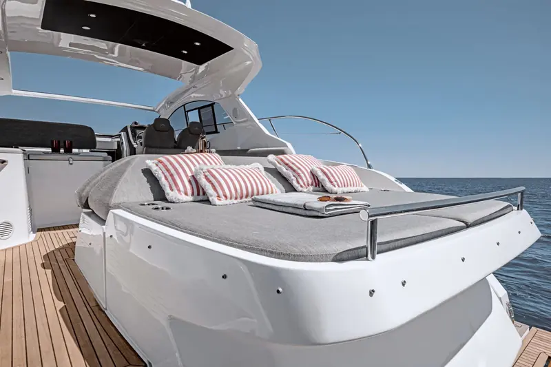 The aft sunpad folds flush with the cockpit seating and carries its own drink holders and a fold-out bolster for the helm side.