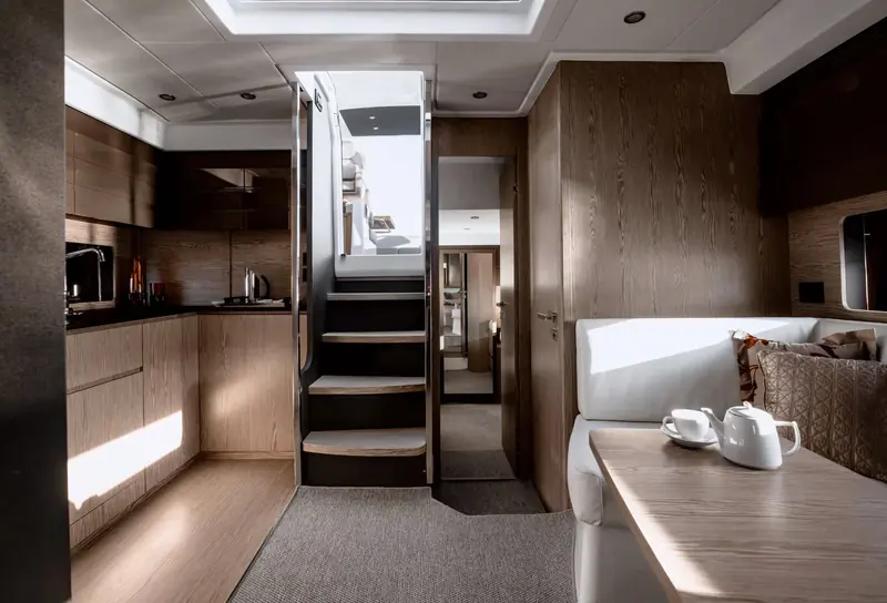 The stairwell down to the lower deck splits the galley from the ensuite guest cabin, lit by a hull-side skylight.