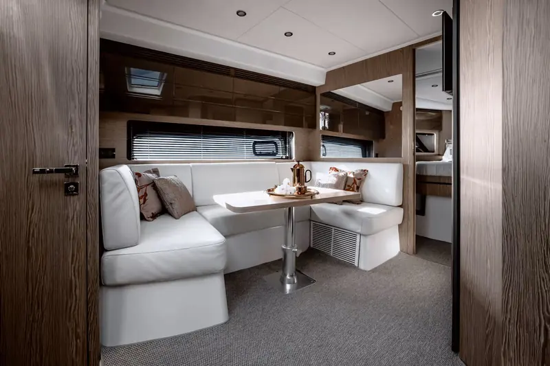 The main-deck dinette in dark wenge-finish joinery, set for coffee opposite the galley run.