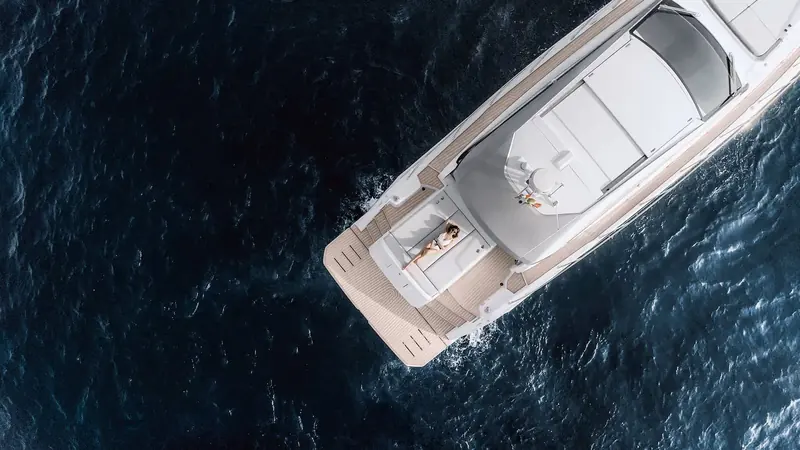 Atlantis 51 idling off Cap d'Antibes with two guests sunbathing on the bow, the sports-cruiser hardtop and low sheer that set the Atlantis line apart from Azimut's flybridge ranges.