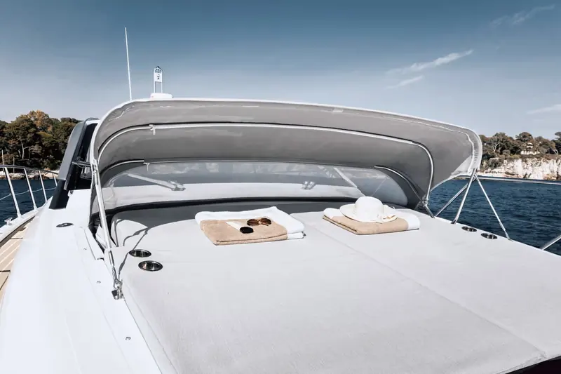 The flybridge-less sundeck forward of the windscreen, towels, sunglasses and a sunhat left out at anchor off the French Riviera.