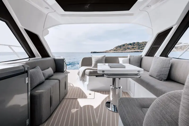 Looking forward from the cockpit toward the helm, the U-shaped seating and drop-down cooler that turn the transom into a second saloon at anchor.