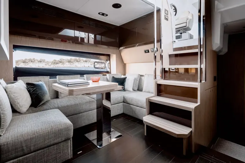 The lower-deck dinette, its portlight glazing set low enough to see the waterline outside, next to the companionway down to the cabins.