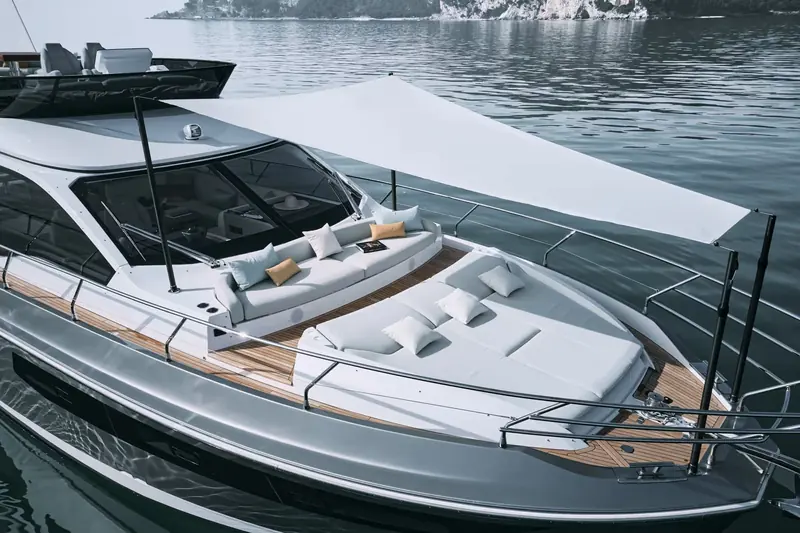 The foredeck lounge shaded by its own bimini, forward of the windscreen and reachable via side decks.