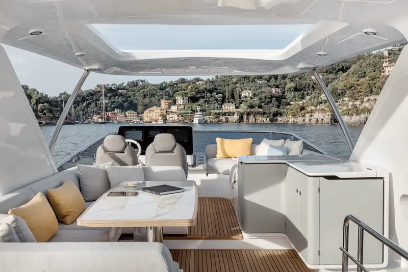Cockpit dining seen from the flybridge stair, with Portofino's harbour visible beyond the transom.
