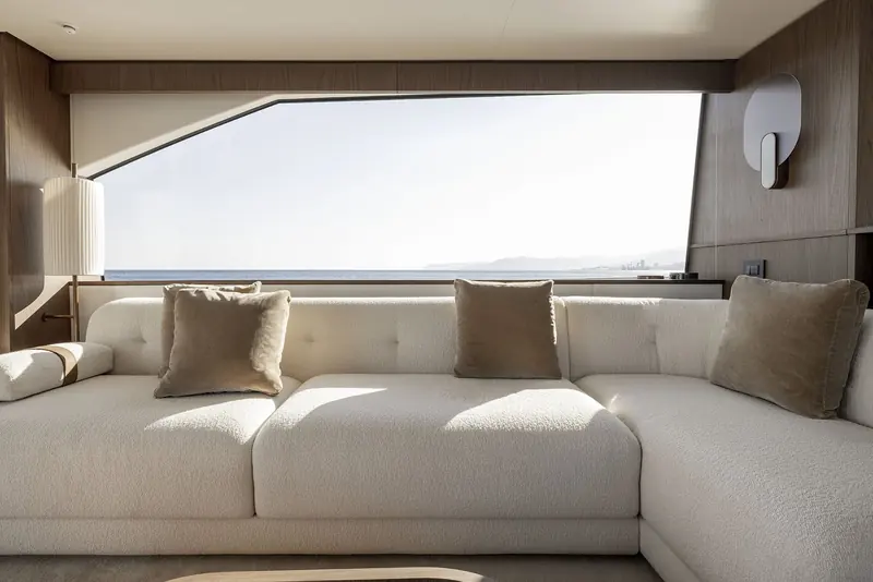 A second saloon view showing the full-height corner glazing, deep L-shaped seating built for a whole group to face the water rather than each other.