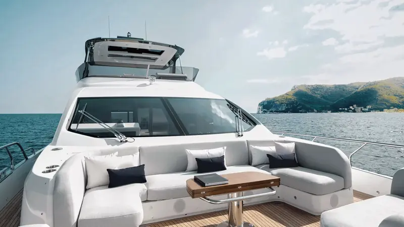 The foredeck lounge and sunpad forward of the windscreen, with a low table built in rather than loose furniture that would need stowing underway.