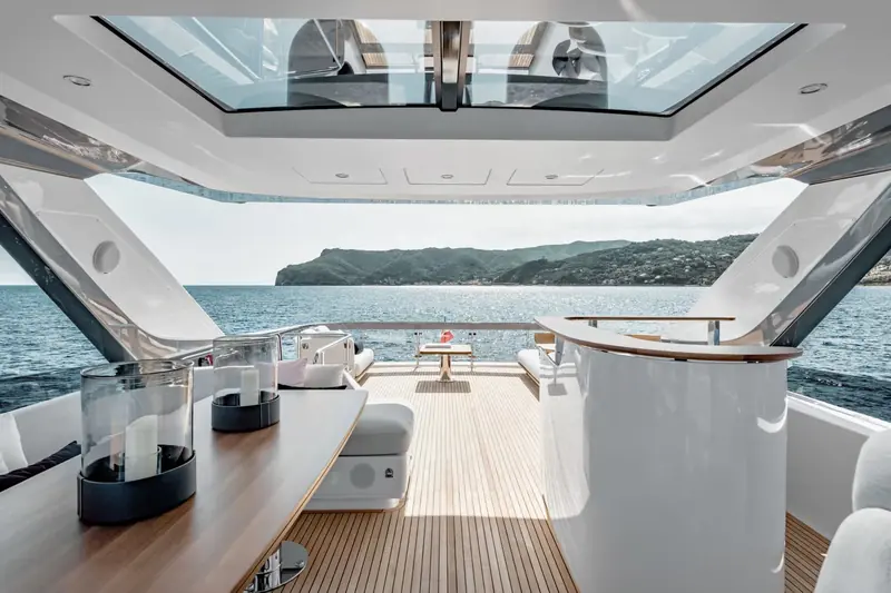 Flybridge wet bar and dining table under the hardtop, positioned so the helm, the bar and the table are all within a few steps of each other.