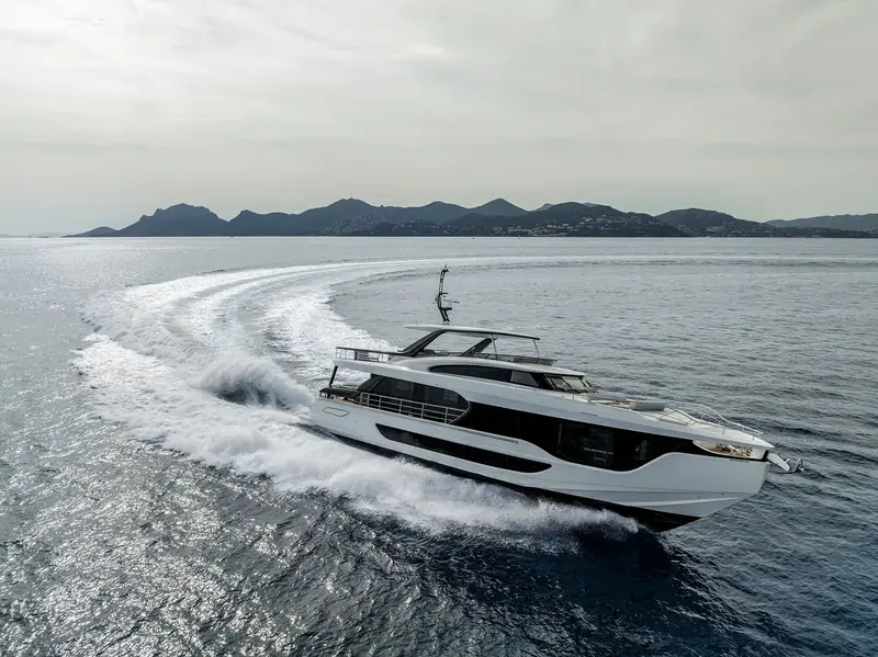 Running hard past the Iles de Lerins, the flared bow throwing a wide, symmetrical wake that shows how little the pod-driven hull digs in at speed.