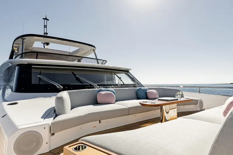 The flybridge aft settee, with the windscreen wipers and radio mast visible against a flat afternoon sea - a working helm deck, not a styling exercise.