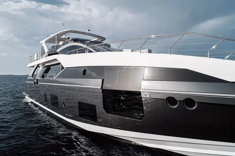 Bow quarter under way off a granite coastline typical of Sardinia's Costa Smeralda, the dark hull livery Azimut offers as an alternative to plain white.