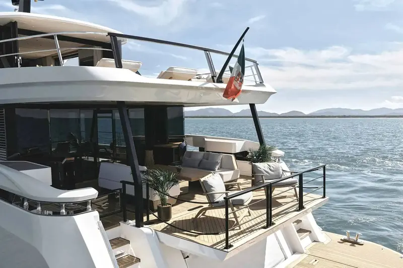 The flybridge saloon opens directly onto the foredeck lounge, glazed on three sides for an open sightline.