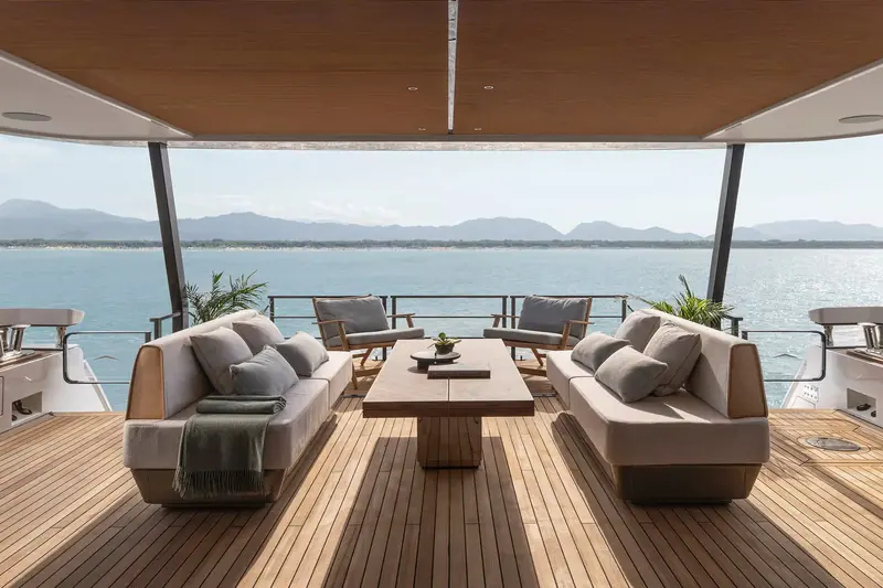 The sky lounge on the upper deck opens fully to the view, wood-lined overhead and furnished as an outdoor living room.