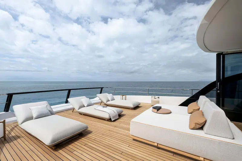 Sunloungers set along the upper deck side decks, shaded by the overhang and facing open water.
