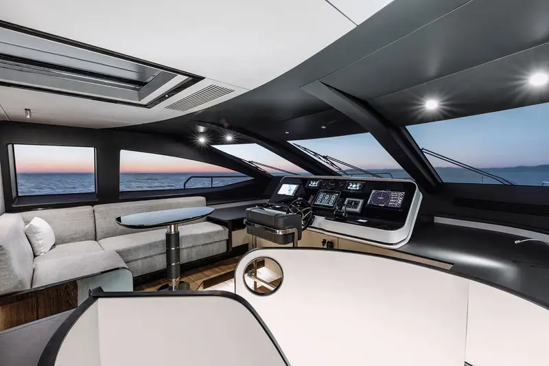 The raised pilot house at dusk, glazed on three sides with the lounge built in behind the helm seats.
