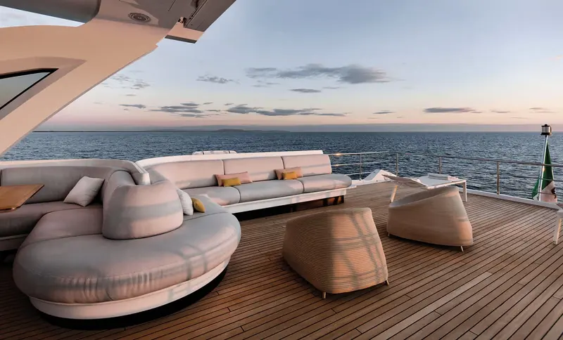 The aft deck lounge at sunset, low-backed seating chosen to keep sightlines open to the water.
