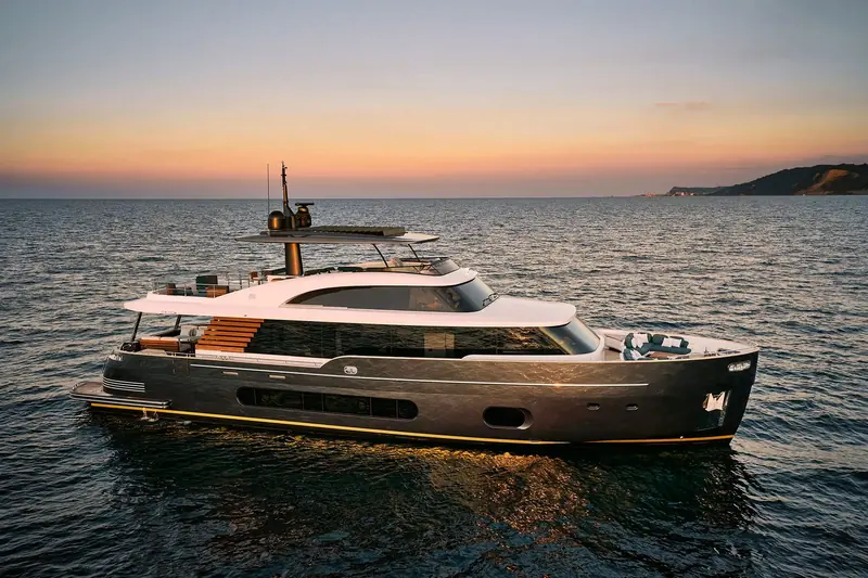 The Magellano 25M at anchor in the last light, her dark hull and gold sheer line breaking up what is otherwise a tall, boxy profile for a 25-metre crossover.