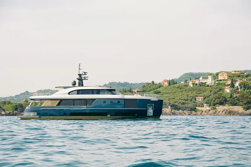 At anchor off a wooded Italian coastline, the dark hull and gold boot-stripe finish Azimut offers on the Magellano line.
