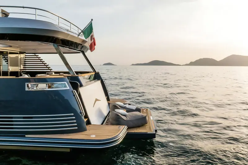 Looking forward from the flybridge at anchor, the Italian courtesy flag and open helm seating visible.