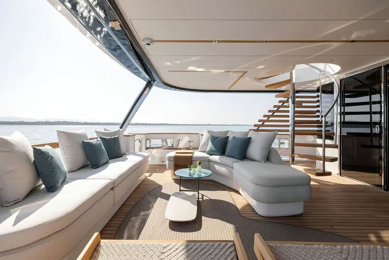The flybridge lounge, a spiral stair down to the main deck built into the same run of seating.
