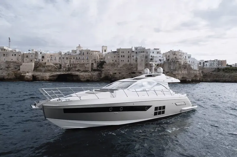 The S6 running past Polignano a Mare on Italy's Adriatic coast, showing the low, glassy coupe profile and forward-raked windscreen that define the S Collection look.
