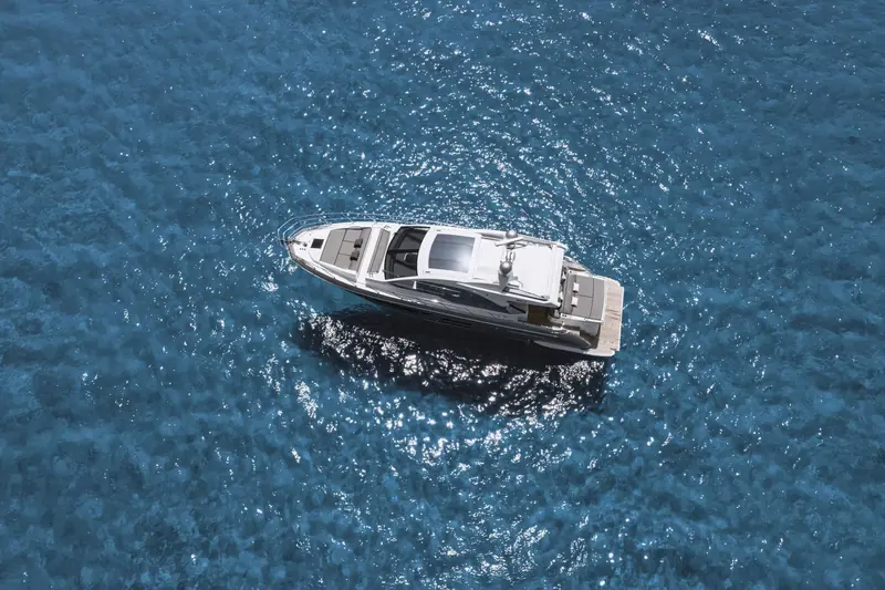 An overhead view underway shows the sportfly hardtop, foredeck sunpad and the tight, symmetrical wake thrown by the triple IPS pod drives.